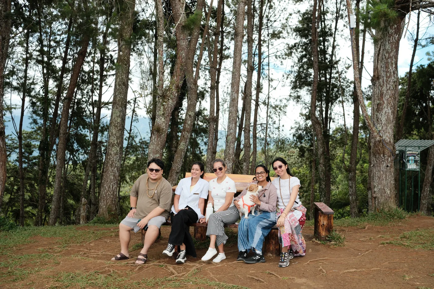 Farm guests together on a wooden bench in the pine grove