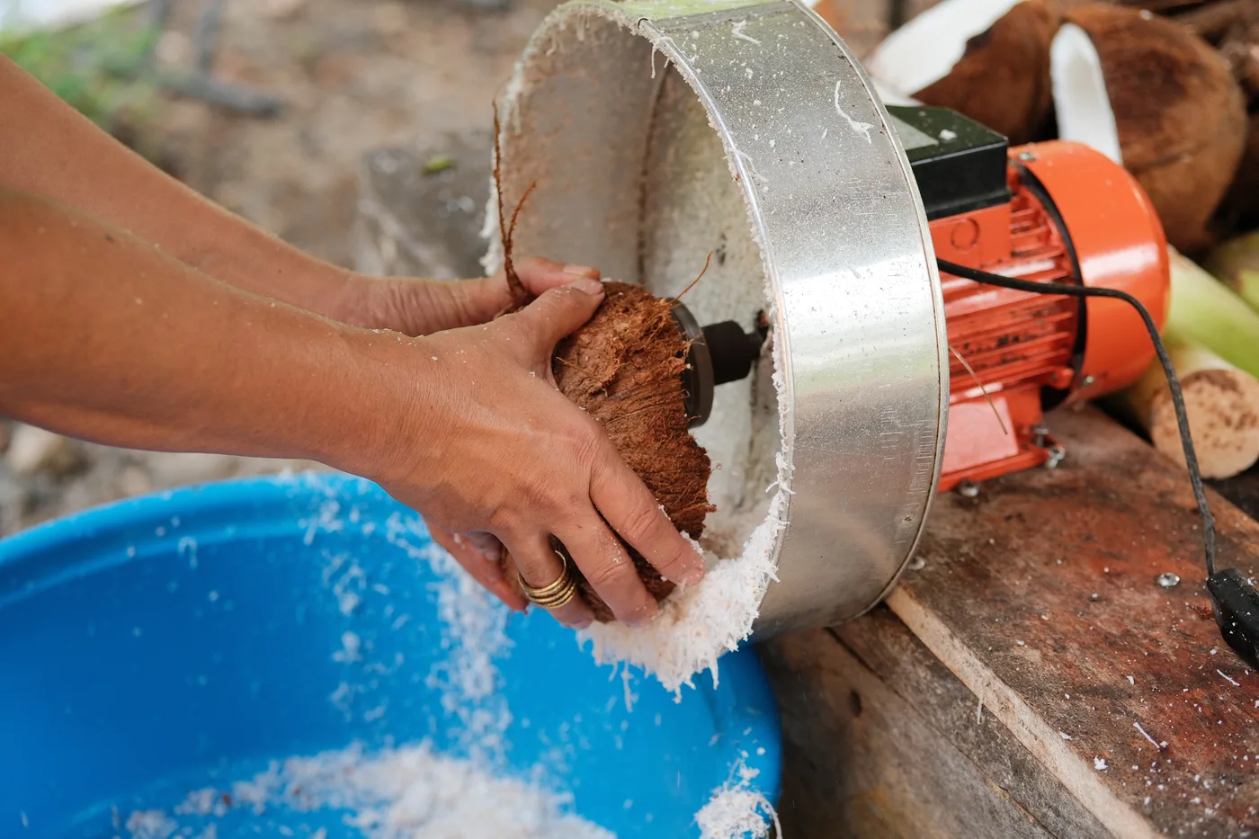 Hands pressing coconut into grater