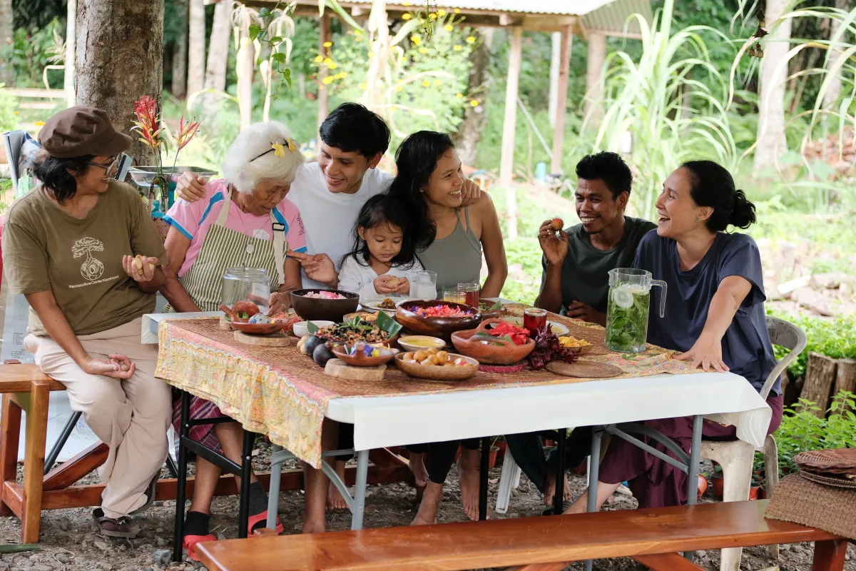 The farm community gathered and laughing over a shared meal at the long table